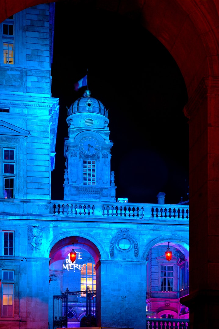 Historic building facade illuminated with blue and magenta neon lighting at night
