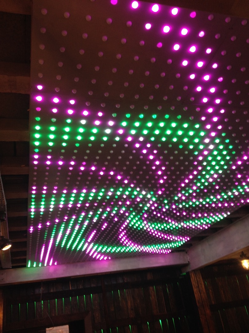 LED light installation on ceiling displaying magenta, green and white programmable lights